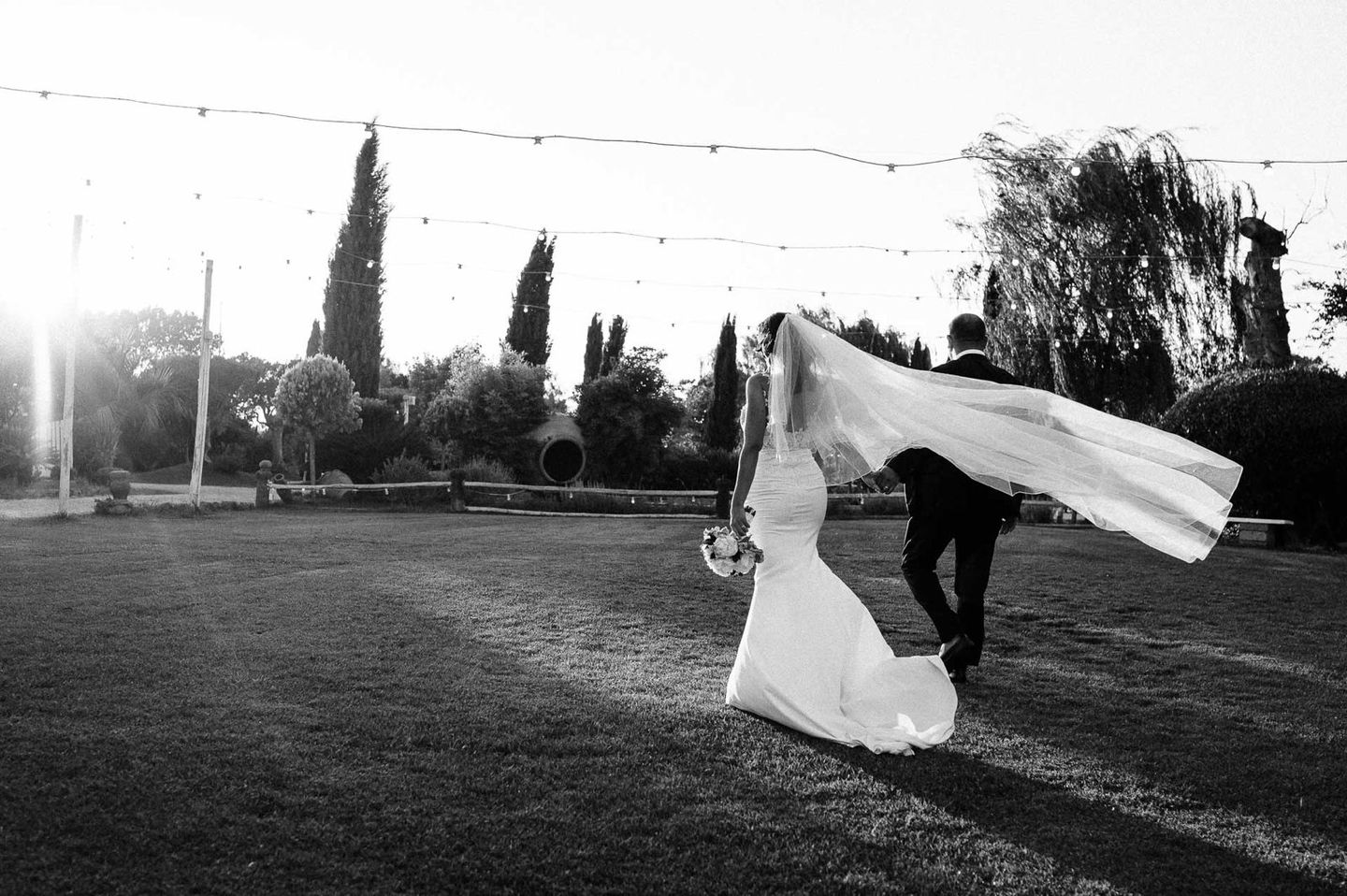 Sposa con velo al tramonto controluce — matrimonio reportage bianco e nero Roma